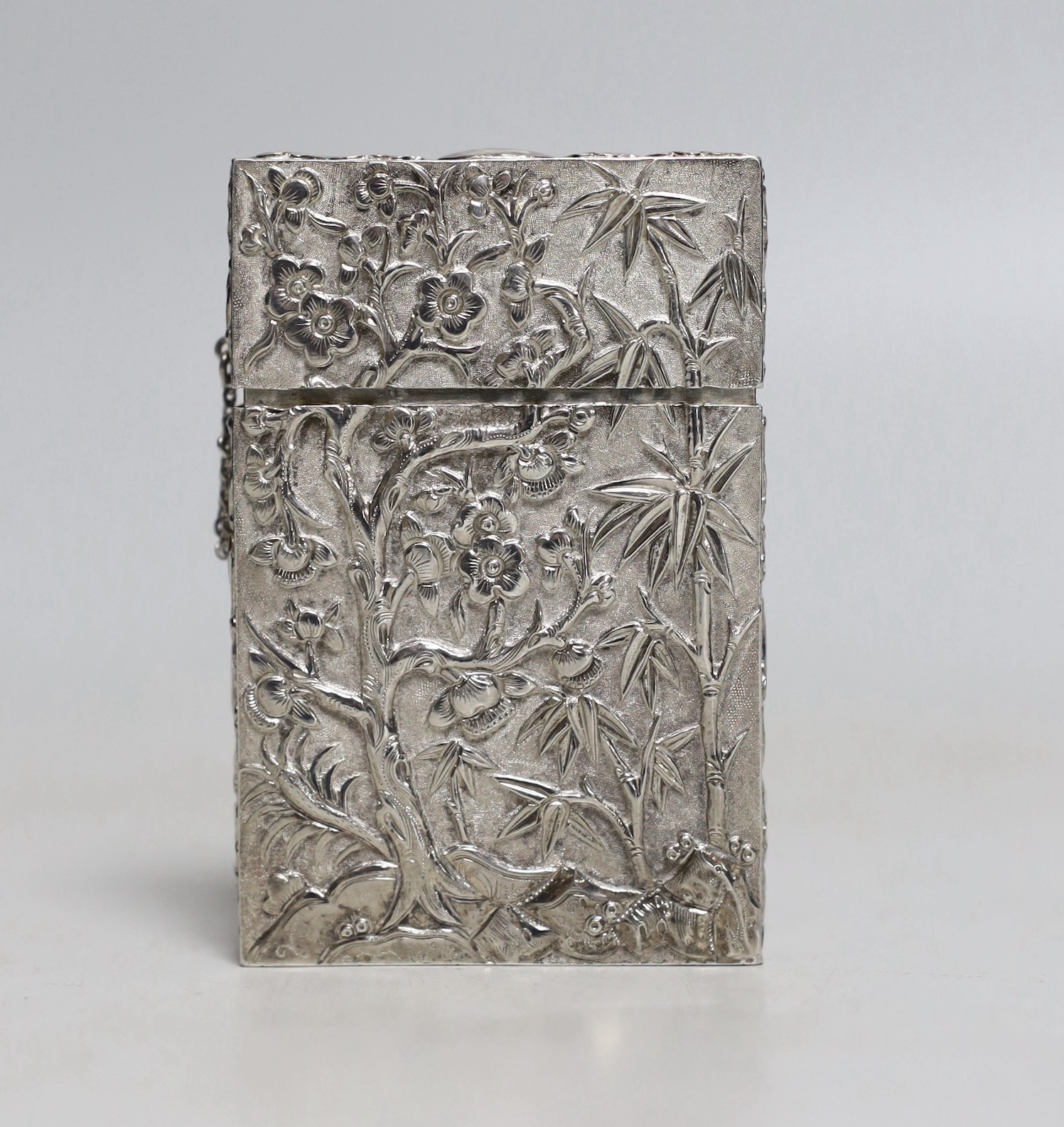 A 19th Chinese Export white metal rectangular card case, by Cutshing, stamped 'CUT', embossed with figured in garden scene and prunus tree, 78mm.